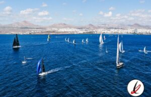 Veleros navegando en el mar de Lanzarote con fondo de montañas y cielo despejado.