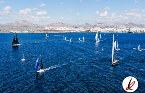 Veleros navegando en el mar de Lanzarote con fondo de montañas y cielo despejado.