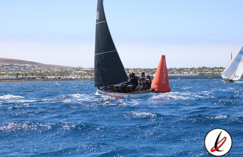Velero deportivo navegando en el mar con tripulación y boya señalizadora, en Lanzarote.