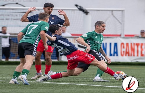 1. Jugadores de fútbol en acción durante un partido en el campo de Lanzarote Deportiva, con jugadores en camiseta verde y azul, en un ambiente de competición en el estadio.