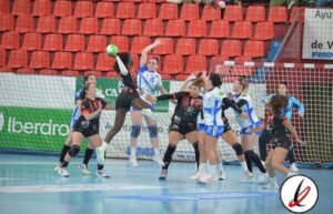 1. Jugadoras de balonmano en acción durante un partido en un recinto cubierto con audiencia.