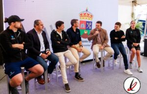 Grupo de jóvenes en una mesa de debate en un evento deportivo en Lanzarote, con un fondo con logotipo oficial y un panel de discusión.