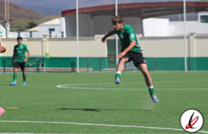 Pase de fútbol en un campo de césped artificial con jugadores en acción durante un entrenamiento o partido.