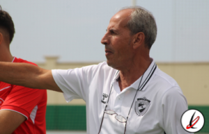 Entrenador de fútbol dando instrucciones a un jugador durante un partido en el campo.