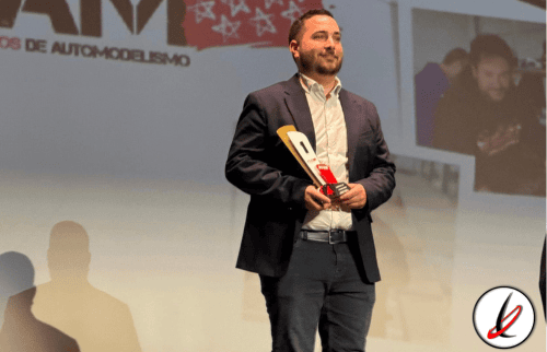 Premio o trofeo entregado a un hombre en un escenario durante un evento deportivo o de reconocimiento.