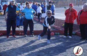 Mujeres mayores jugando a la petanca en un campo de tierra, vestidas con ropa deportiva y gafas de sol, en un día soleado en Lanzarote.