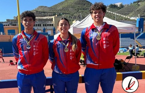 Tres atletas con medallas en un evento deportivo en un estadio al aire libre en Lanzarote.