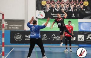 1. Portero en acción en un partido de balonmano en un polideportivo con espectadores sentados en el fondo.
