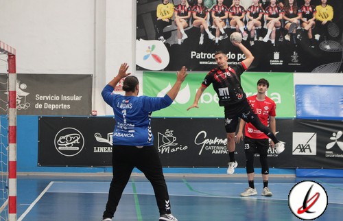 1. Portero en acción en un partido de balonmano en un polideportivo con espectadores sentados en el fondo.