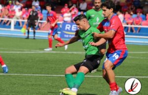 Jugador en verde intentando controlar el balón mientras es presionado por un oponente en un partido de fútbol en Lanzarote.
