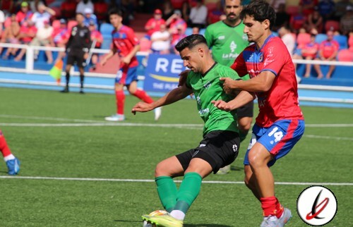 Jugador en verde intentando controlar el balón mientras es presionado por un oponente en un partido de fútbol en Lanzarote.