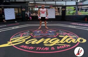 Jugador de Muay Thai en el ring de un gimnasio, con logotipo de Bangtao Muay Thai & MMA en el suelo.