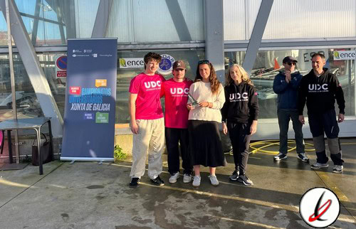 UDC y UIZ en una estación de transporte, grupo de cinco personas posando para la foto, algunos con ropa deportiva y otros con ropa casual, fondo con carteles y estructura de vidrio.