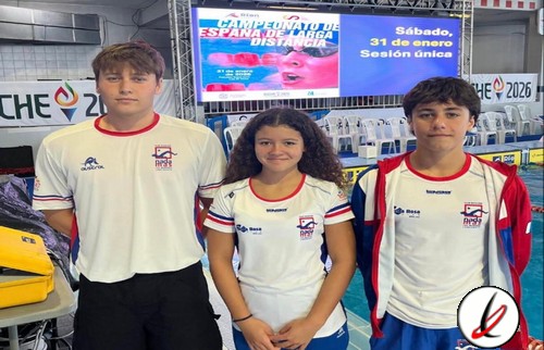 Tres jóvenes deportistas con camisetas blancas en una piscina cubierta, listos para competir en un evento de natación.
