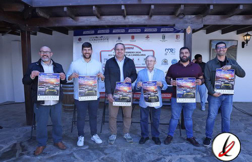 Línea 1: Participantes en evento deportivo en Lanzarote, sosteniendo carteles promocionales en un espacio cubierto con estructura de madera.