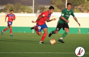 Jugadores de fútbol en acción durante un partido en el campo de césped artificial.