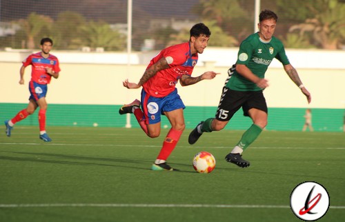Jugadores de fútbol en acción durante un partido en el campo de césped artificial.