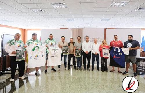 Jugadores de fútbol en una ceremonia de premiación, algunos con camisetas y otros con prendas de vestir formales, en un espacio interior con suelo de mármol y paredes blancas.