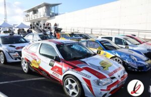 Coches de carreras en la parrilla de salida en un circuito de Lanzarote, con varios vehículos deportivos preparados para una competición.