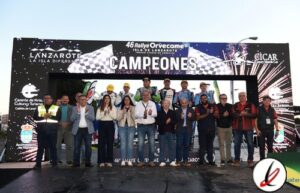 Campeones del 46º Rallye Orvecame Isla de Lanzarote, grupo de personas celebrando en la ceremonia de premiación en un escenario con cartel de "Campeones".