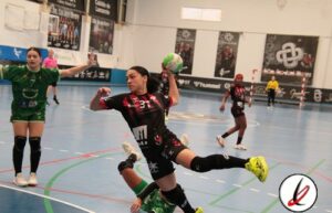 Jugadora de balonmano en acción lanzando el balón en un partido en interiores, con otras jugadoras y portero en el fondo, en una cancha cubierta de Lanzarote Deportiva.