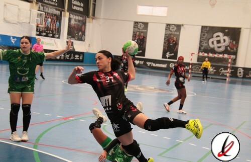 Jugadora de balonmano en acción lanzando el balón en un partido en interiores, con otras jugadoras y portero en el fondo, en una cancha cubierta de Lanzarote Deportiva.