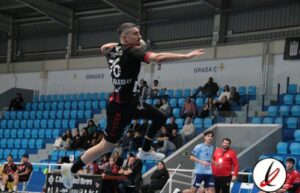 Saltador en un partido de voleibol en un estadio cubierto, con jugadores y espectadores en el fondo, durante una competición deportiva en Lanzarote.