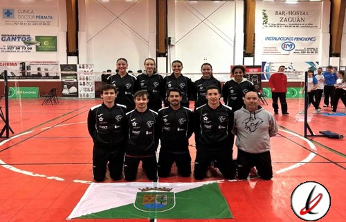 Equipo de voleibol masculino con uniforme negro, posando en una cancha cubierta con bandera de Lanzarote, en un evento deportivo indoor.