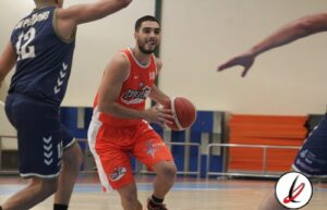 Pase de baloncesto en un partido, jugador con camiseta roja, en acción en la cancha.