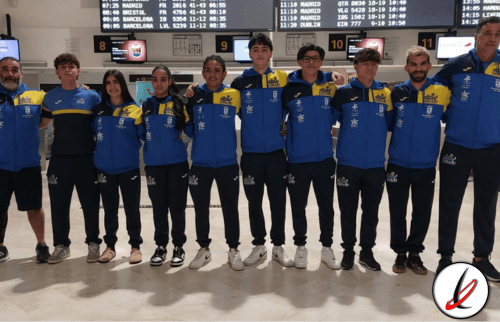 Jugadores de un equipo deportivo en aeropuerto, con uniformes azules y amarillos, posando juntos para una foto grupal antes de viajar a una competencia.