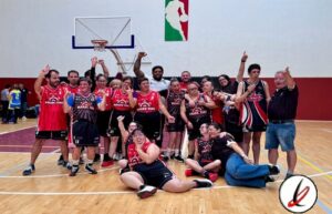 Equipo de baloncesto celebrando en la cancha con jugadores, entrenador y público, en un ambiente de victoria y alegría.